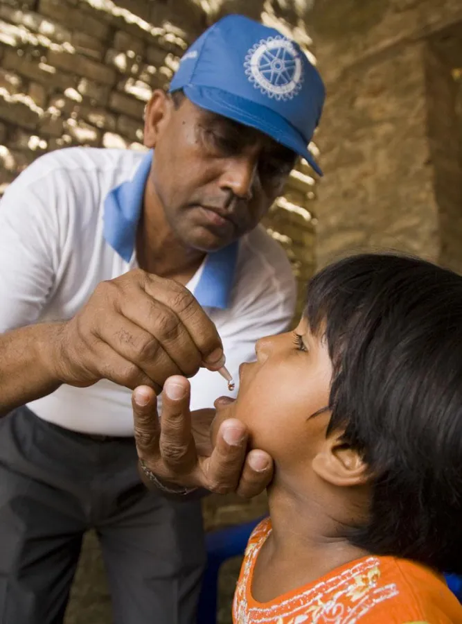 Zwei Tropfen, die Leben retten können. Rotarier impft Kind gegen Polio.
