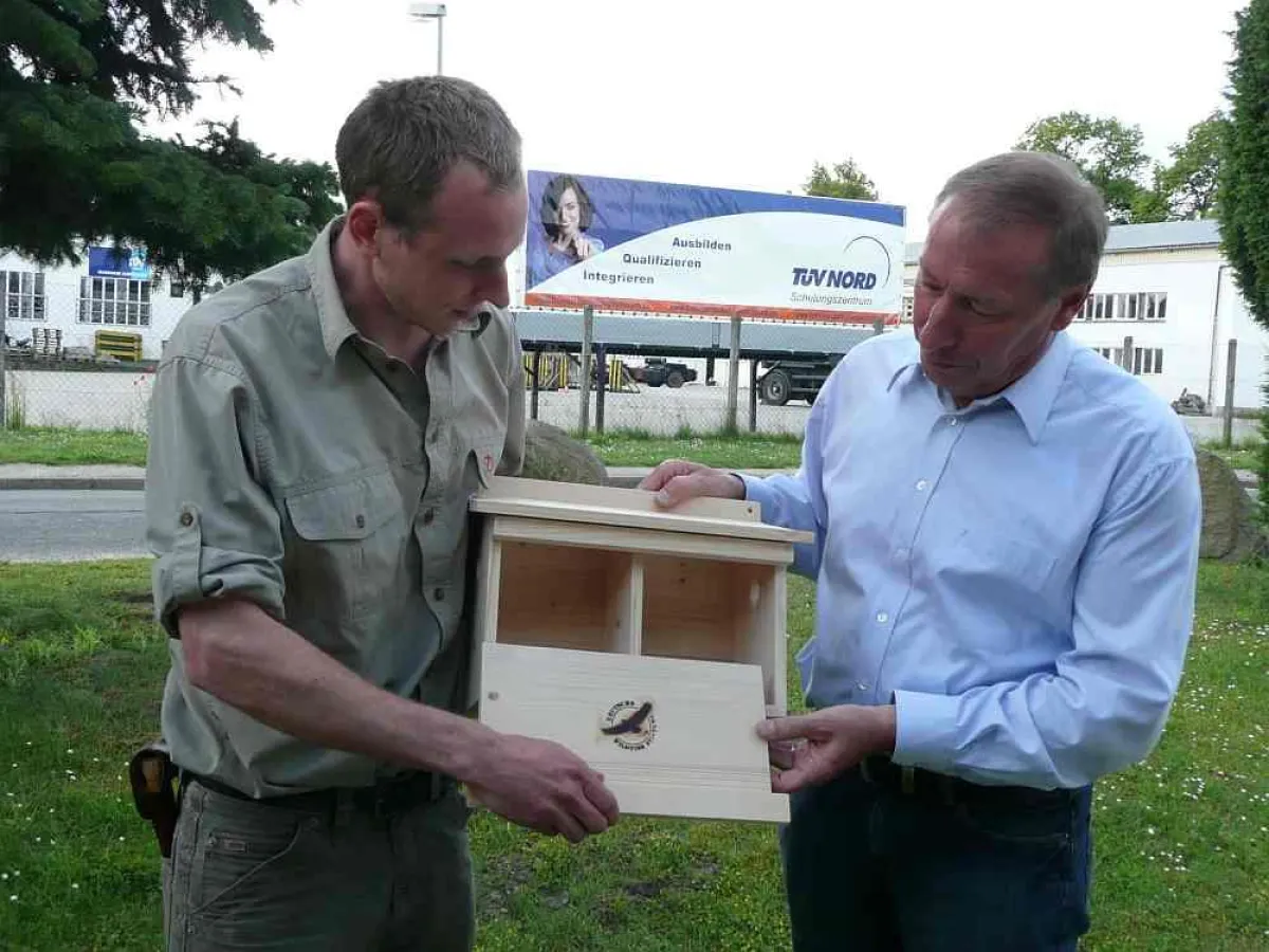 Zum Auftakt der Zusammenarbeit übergibt Martin Thurley von der Deutschen Wildtier Stiftung das erste Spatzen-Reihenhaus an Geschäftsstellenleiter Fritz Lorenz, TÜV NORD Schulungszentrum.