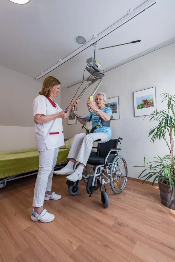 Umhänge-Deckenlifter mit Hebebügel „Helfende Hände“ im Einsatz in einem Altenwohnheim.