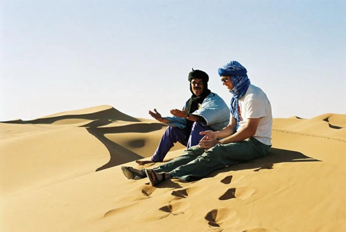 Reisender im Gespräch mit dem Wüstenführer auf einer der hohen Sanddünen des Erg Chebbi