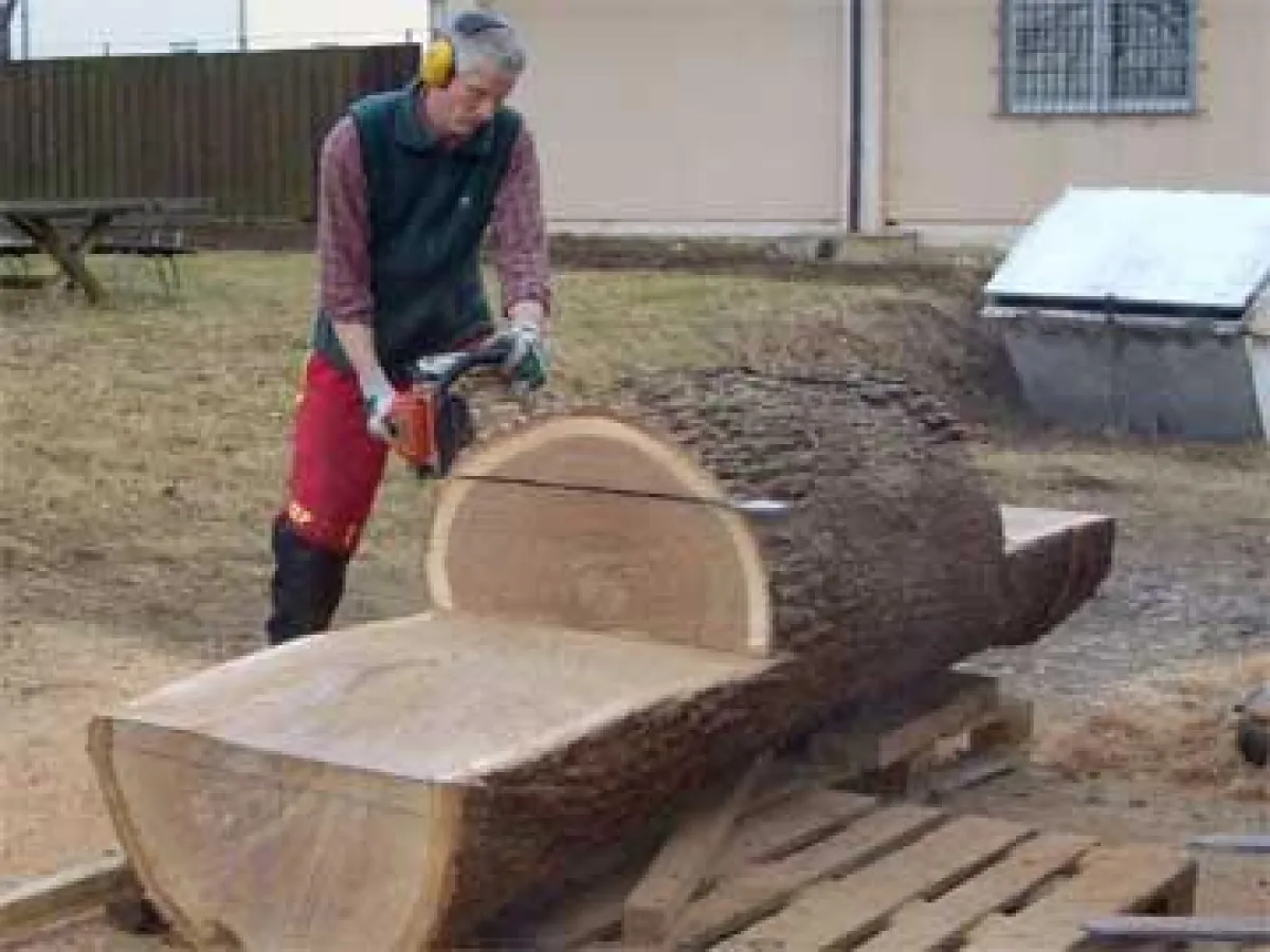 Dass zur Möbelproduktion der Naturstoff Holz erforderlich ist, daran soll eine Stuhlskulptur erinnern, die in Bad Boll aus einem Eichenstamm herausgerabeitet wird.