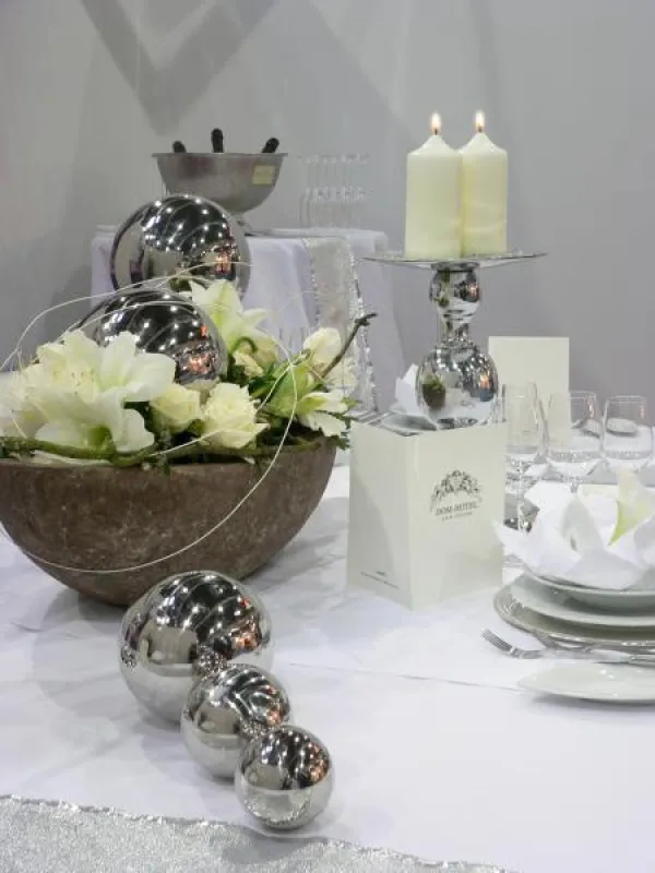 Silberne Accessoires und Stumpenkerzen mit dem RAL-Gütezeichen veredeln jede Festtafel. Foto: Gütegemeinschaft Kerzen; Deko: Dom-Hotel, Köln