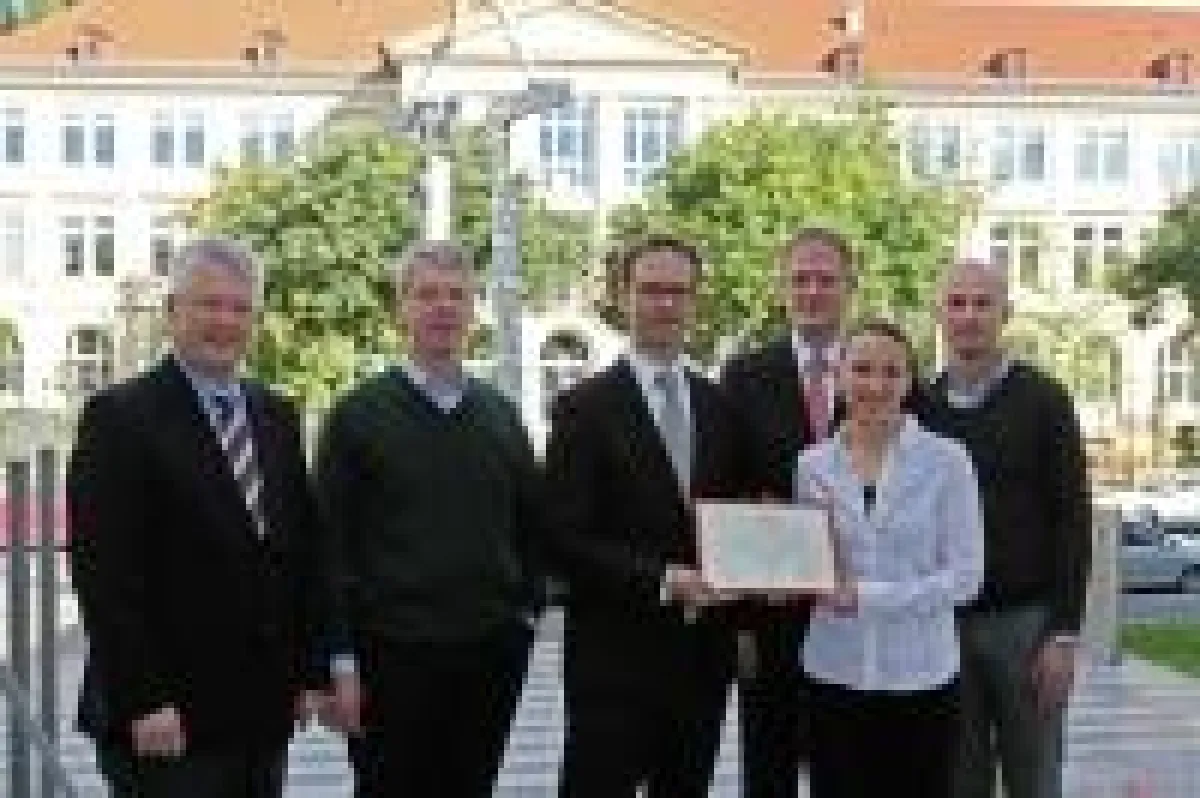 Dr. Frank Stehr (3.v.l.), Leiter Forschung der NCL-Stiftung, übergibt im Beisein von Prof. Heinz Reichmann (l.), Dekan der Medizin