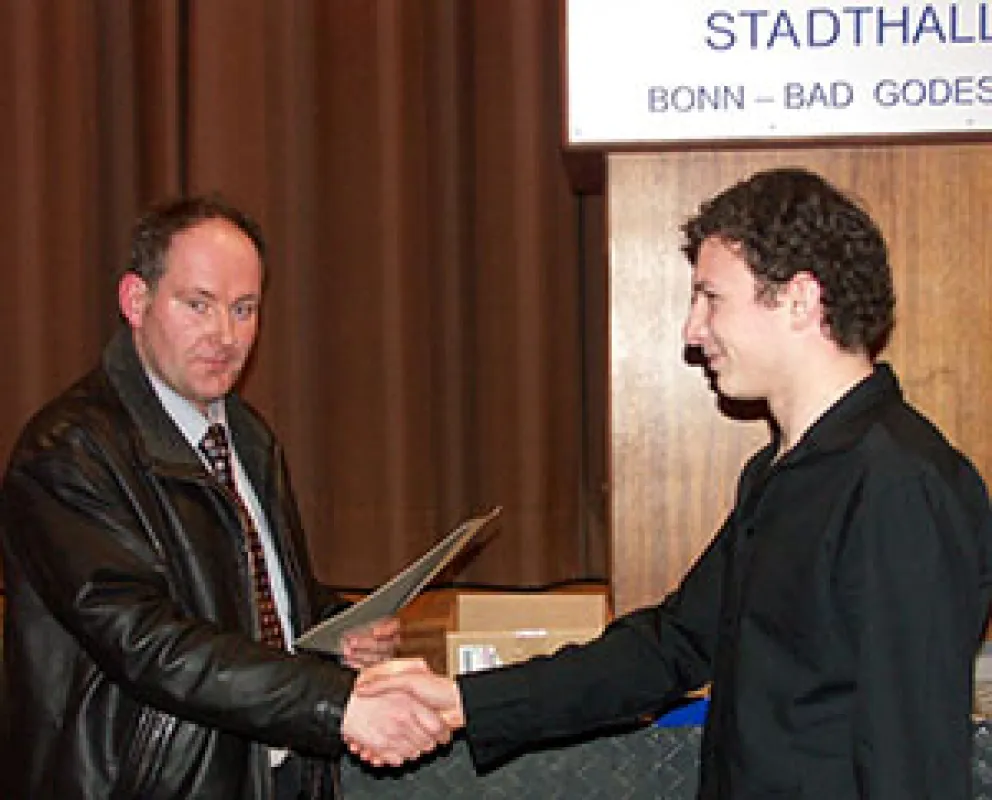 Foto: Norbert Metzen, Vorsitzender der Prüfungskommission, beglückwünscht Artur Rempel (rechts) bei der Lossprechung der Gesellen in der Bad Godesberger Stadthalle.