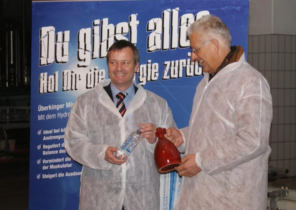 Heinz Breuer [r.] zeigt Klaus Riegert [l.] die Überkinger-Entwicklung vom Tonkrug hin zur modernen Marken-PET-Flasche