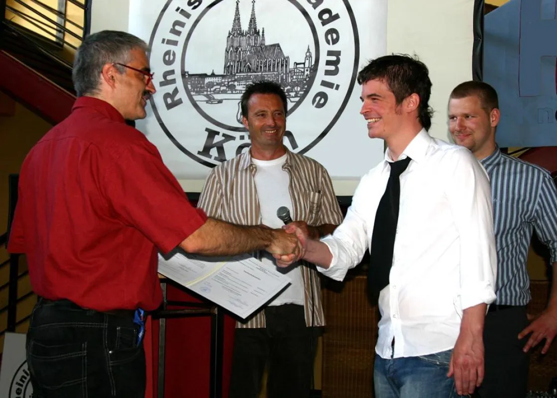Klassenlehrer Ralf Albert und Helmut Delzepich, Leiter der Fachschule für Technik, überreichen das Zeugnis einem Absolventen der Medizintechnik.