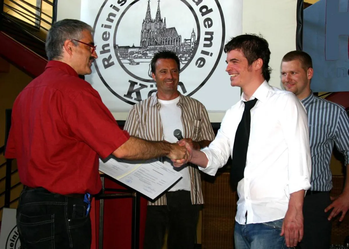 Klassenlehrer Ralf Albert und Helmut Delzepich, Leiter der Fachschule für Technik, überreichen das Zeugnis einem Absolventen der Medizintechnik.