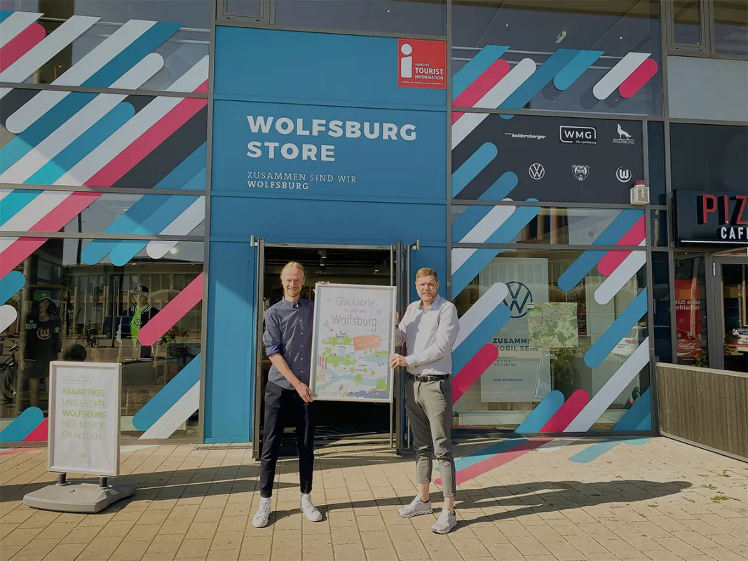 Jonas Lamberg und Christoph Kaufmann präsentieren das Buch „Glücksorte in und um Wolfsburg“ (© WMG Wolfsburg)