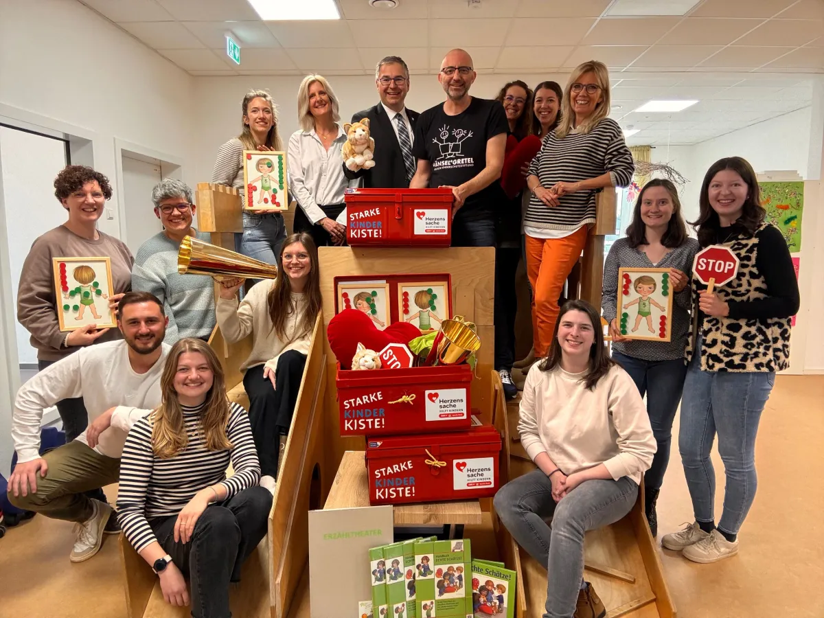 OB Nico Morast + Jerome Braun (an der roten Kiste), VertreterInnen der 11 Kitas/des Trägervereins (© Jerome Braun, Dt. Kinderschutzstiftung Hänsel+Gretel)