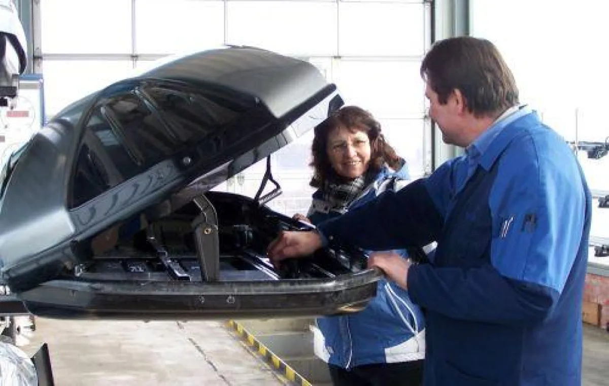 TÜV-Stationsleiter Alexander Fenner erklärt einer Kundin die Vorteile einer Dachbox.