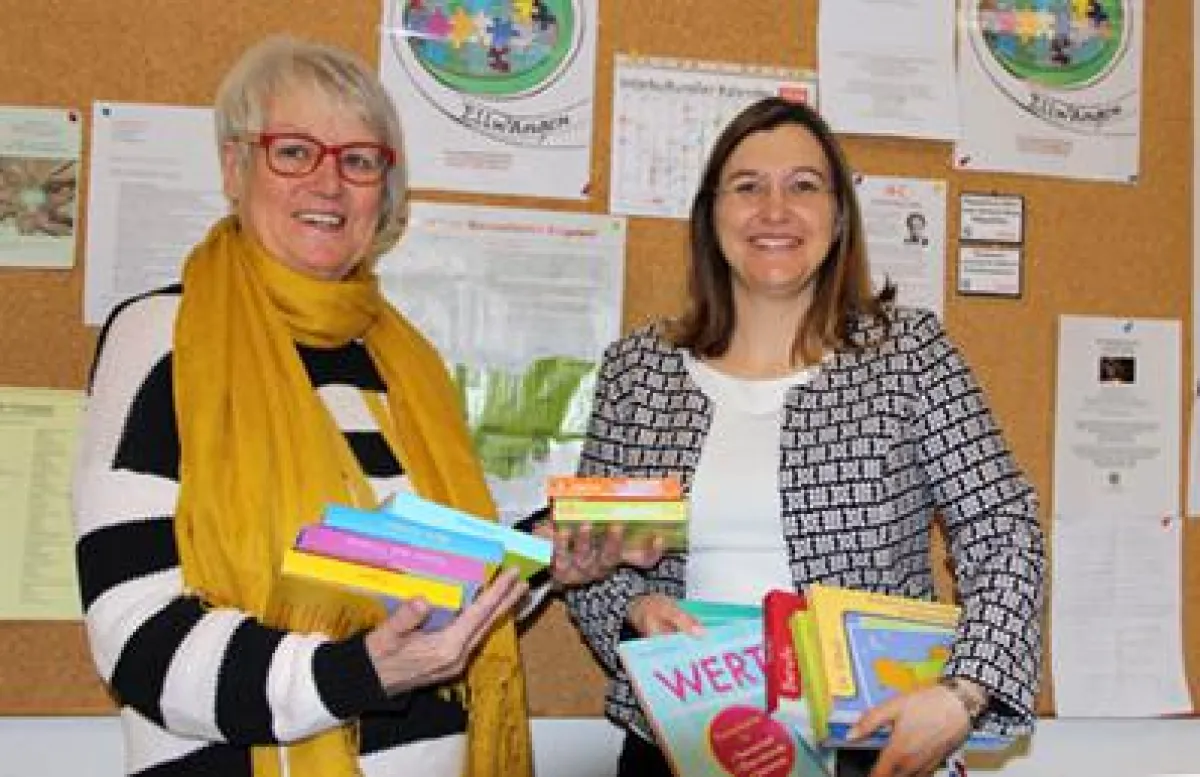 Tina Betzold (rechts) übergibt Elisabeth Hild kostenlose Unterrichtsmaterialien.