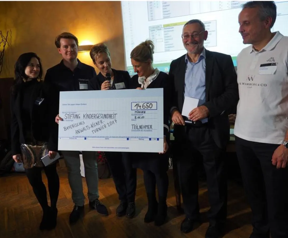 Scheckübergabe an die Stiftung auf dem Bayerischen Anwalts-Kickerturnier 2017; v.l.n.r.: Dr. jur. (Ung.) F. Weinhardt (Kanzlei Wach + Meckes LLP), Dr. M. Braun (Kanzlei Gleiss Lutz),  (Dr. K. Bergmann