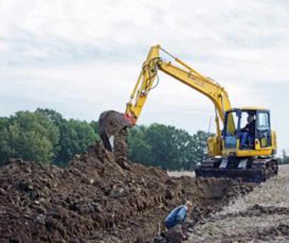 Mit Drainagelöffel arbeitet sich der stabile Komatsu PC 138-US-8 aus dem HKL MIETPARK durch den nassen Feldboden.