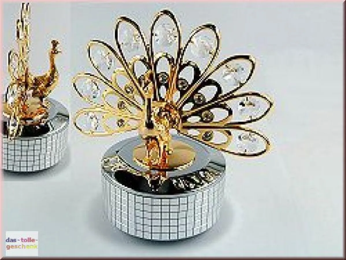Die Melodie MEMORIES aus dem Musical CATS erklingt aus dieser kunstvoll gearbeiteten Spieluhr. Vergoldeter Pfau mit Swarovski-Kristallen. Größe: 137 x 134 mm.