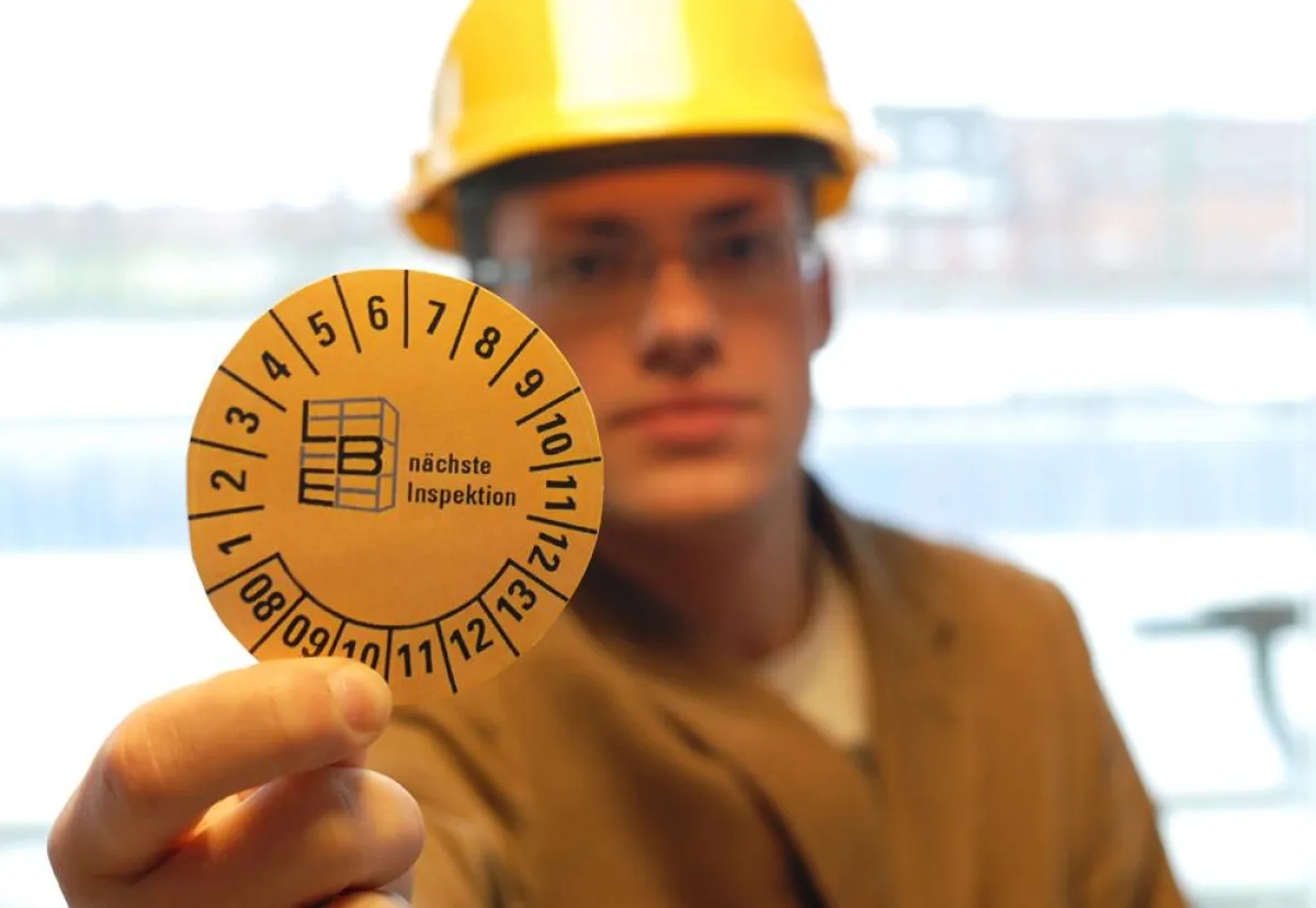 Der Regalinspekteur belegt seine Kontrolle mit einer Prüfplakette