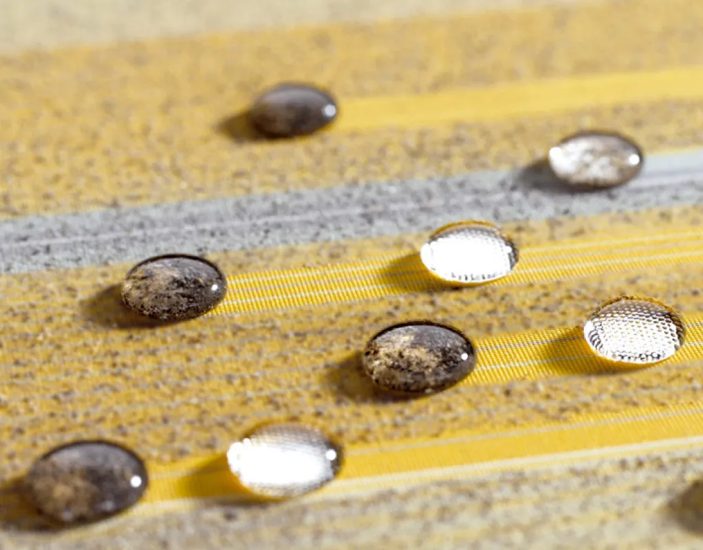 Erster Testlauf auf der mit Nanopartikeln veredelten Oberfläche des Markisentuchs sunsilk® SNC aus dem Hause Schmitz. Die Siegeltropfen perlen problemlos ab und nehmen Schmutzpartikel mit.