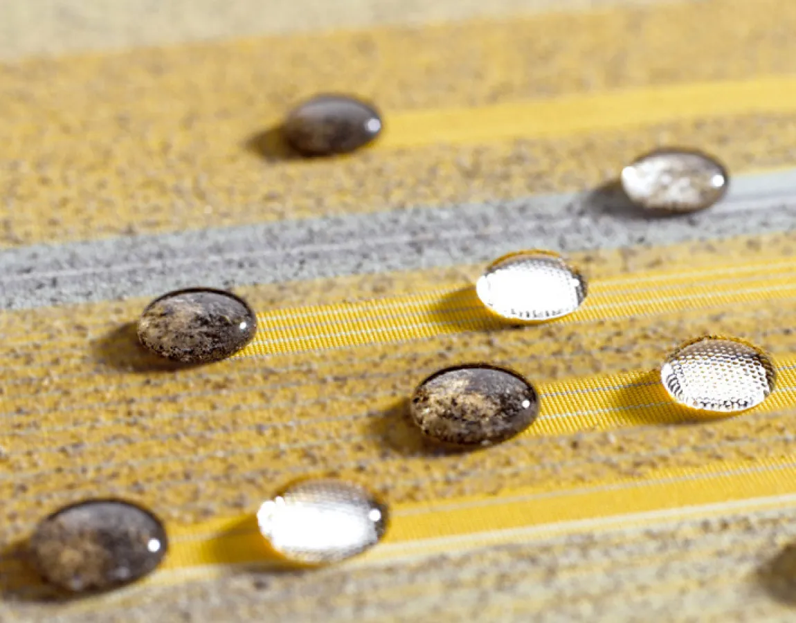 Erster Testlauf auf der mit Nanopartikeln veredelten Oberfläche des Markisentuchs sunsilk® SNC aus dem Hause Schmitz. Die Siegeltropfen perlen problemlos ab und nehmen Schmutzpartikel mit.