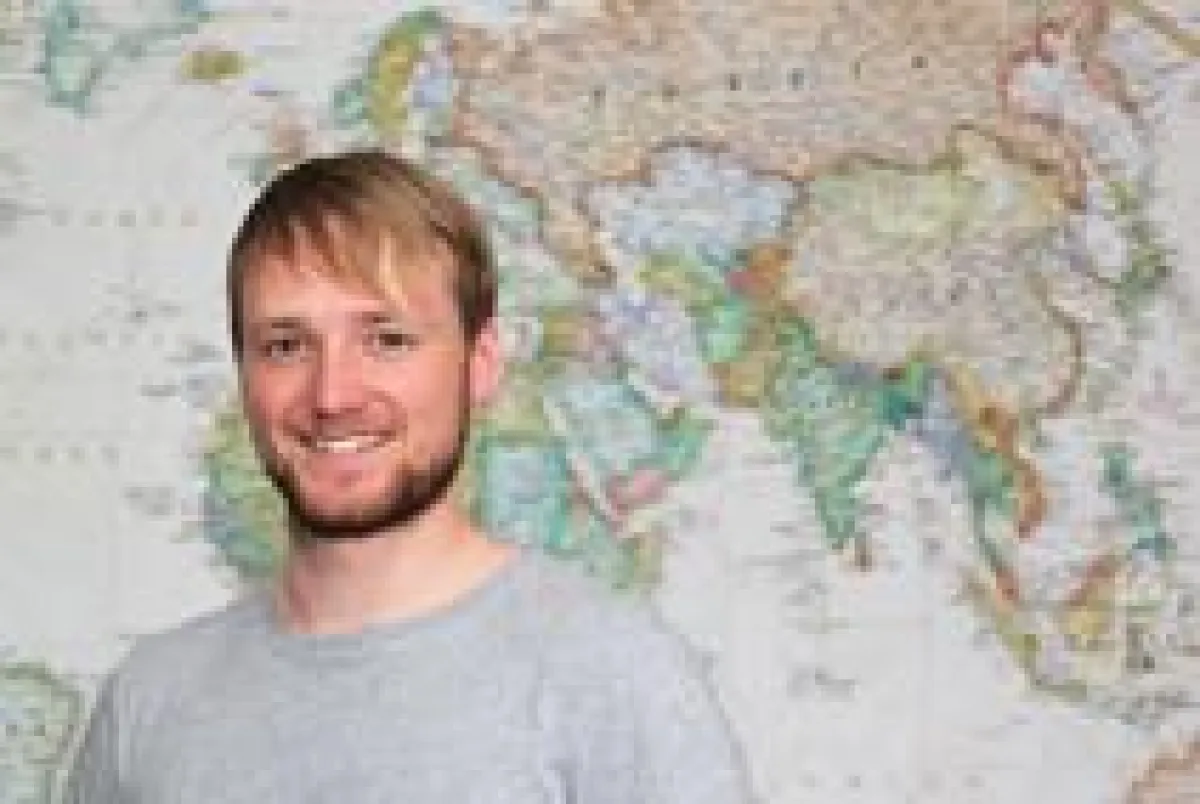 Geschäftsfüher Andre Lutter vor handgemalter Weltkarte