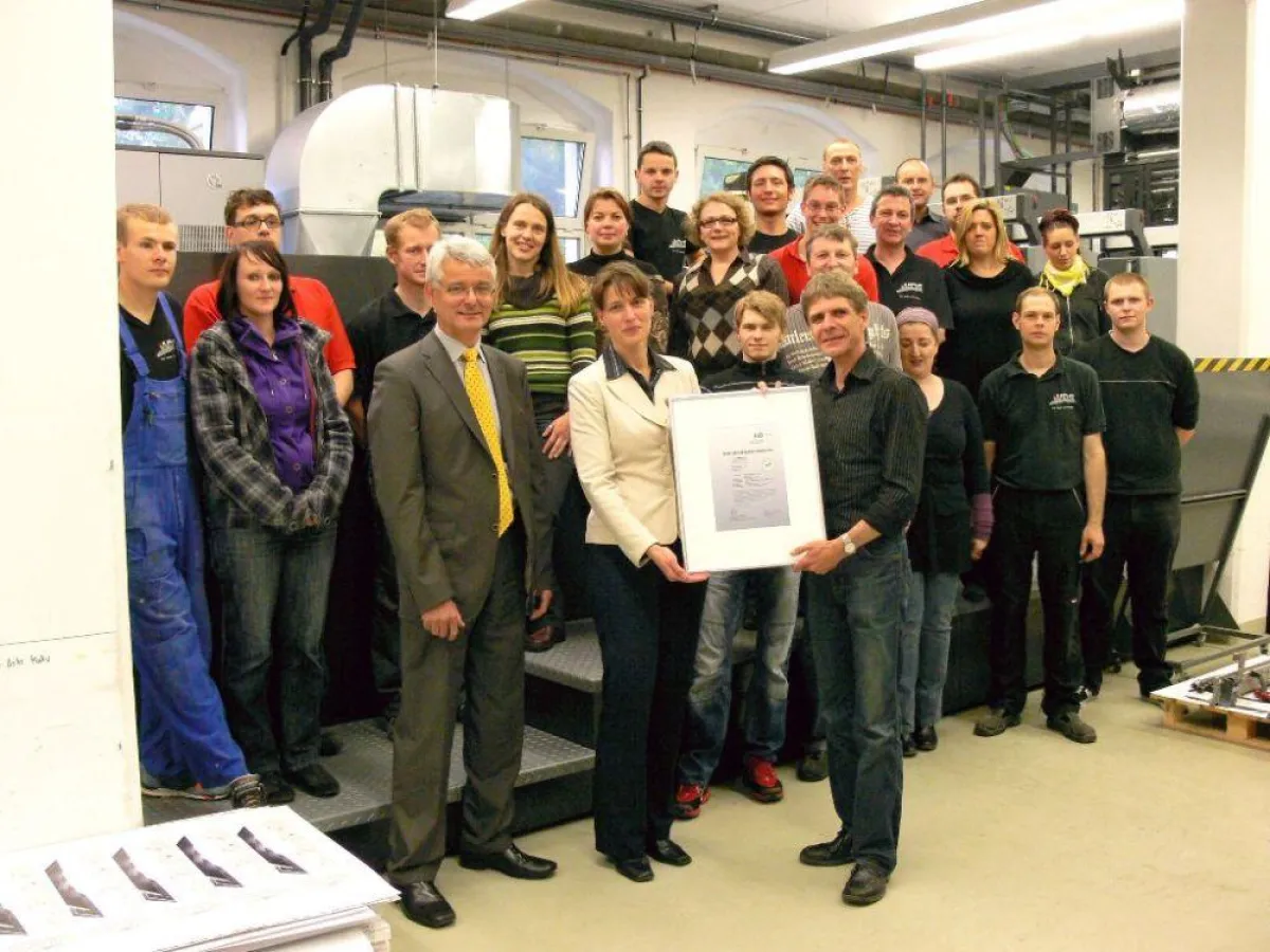 Urkundenübergabe im Kreis der Belegschaft. Im Vordergrund Jürgen Stopporka und Beatrix Genest (beide SID) und Thomas Pertermann (v.l.n.r.)