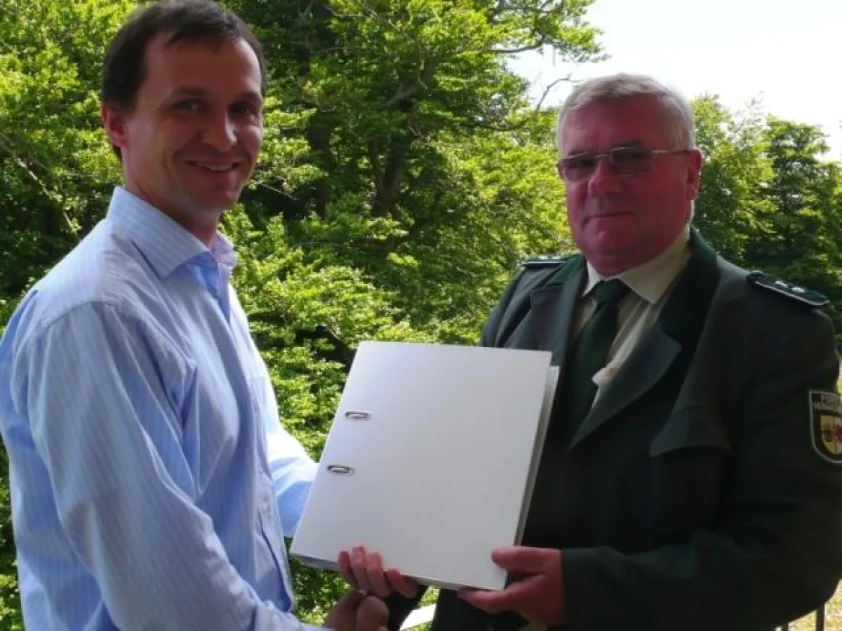 Ulf Steiner, Geschäftsführer des Nationalpark-Zentrums KÖNIGSSTUHL, übergibt die Machbarkeitsstudie an Siegfried Brosowski, Leiter des Nationalparkamtes Vorpommern