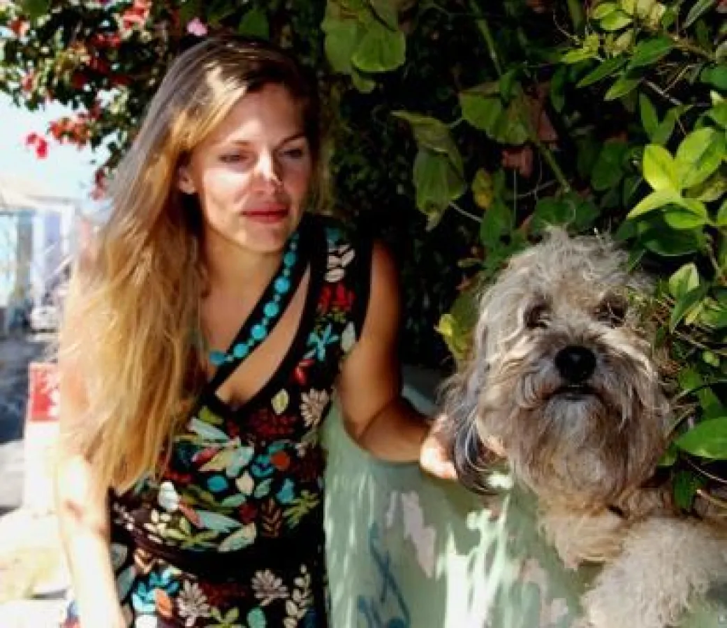 Die Moderatorin Martina Hirschmeier besucht einen Straßenhund an seinem Plätzchen in einer Hecke.