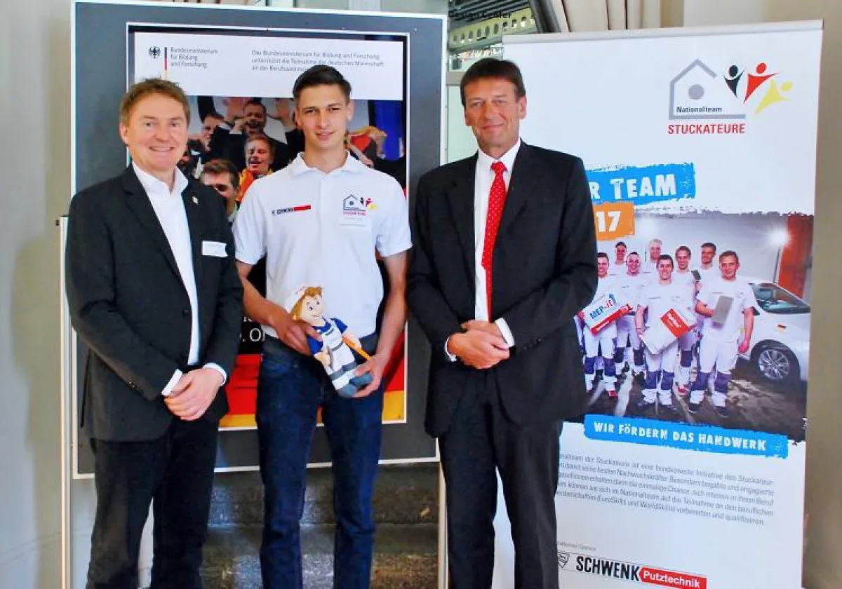 Lukas Kirschmer (Mi.) bekommt von Thomas Sondermann (re.) einen Glücksbringer für die WorldSkills