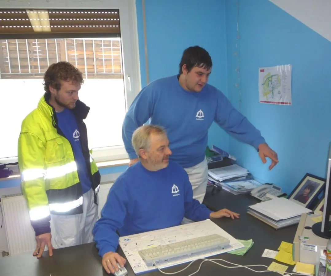 Das Bild zeigt Ingo Porzel , den Leiter des Asklepios-Fahrdienstes sitzend mit seinen Mitarbeitern Antonio Manelli (rechts) sowie Thomas Colell bei der Einsatzplanung.