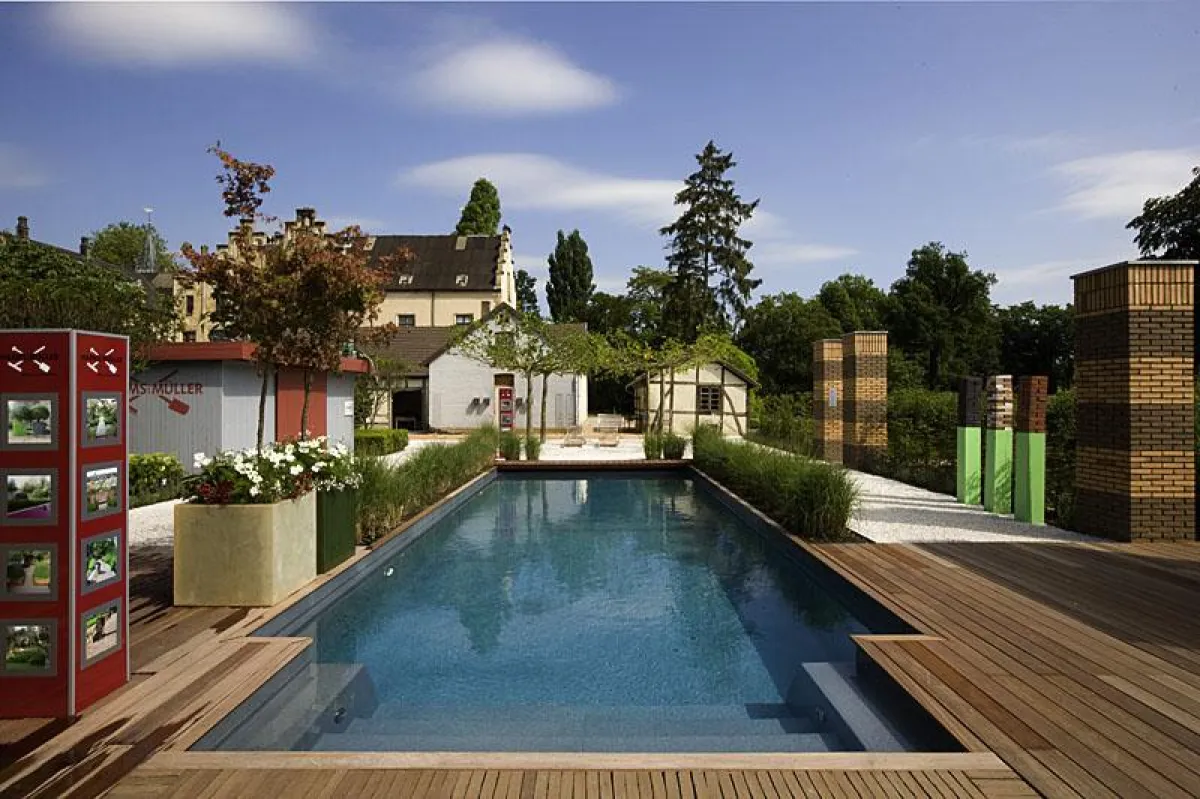 Pool und Schlossgarten verschmelzen zu einer Einheit. Der rechteckige Pool fügt sich wie selbstverständlich in die natürliche und zugleich künstlerisch anmutende Umgebung ein.