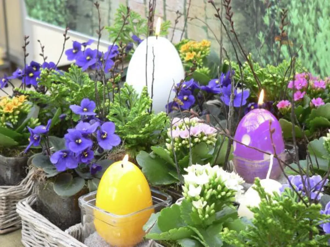 Schnelle Frühlingsdeko für Drinnen oder Draußen: In einer ausrangierten Holzkiste werden verschiedenfarbige Eierkerzen mit dem RAL-Gütezeichen je nach Belieben in Gläschen zwischen den Pflänzchen posi