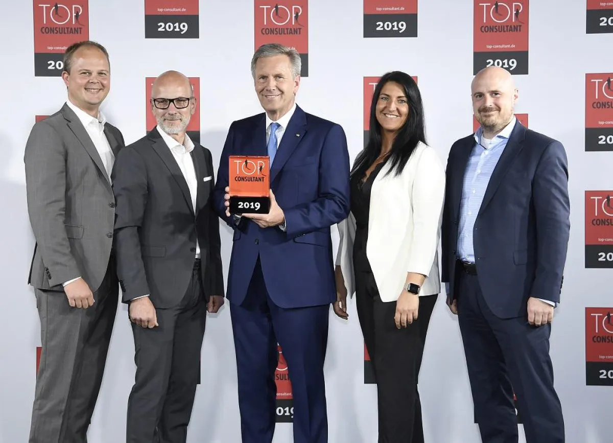 Mentor Christian Wulff übergibt die TOP CONSULTANT Trophäe an das Team von bluecue