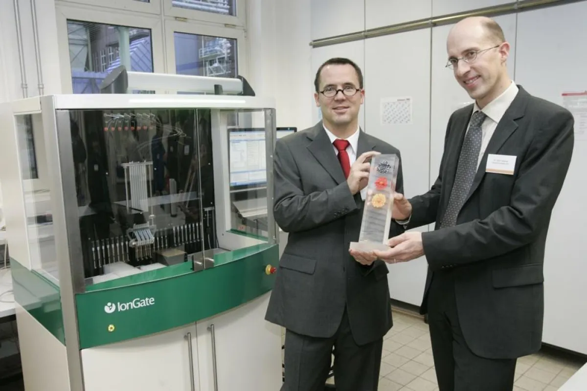 Dr. Thiemo Gropp, Geschäftsführer IonGate Biosciences GmbH (links) und Dr. Björn Mamat, Expert Team Life Sciences Deutsche Bank AG Frankfurt (rechts) mit dem Preis vor der SURFE2R Workstation 5000, de