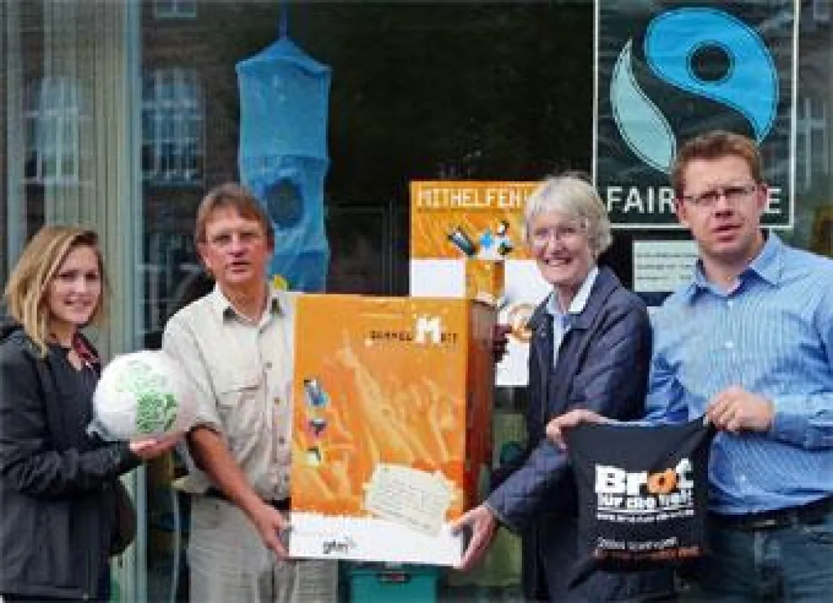 Carla Russell vom Eine-Welt-Kreis Emsdetten (r.) nimmt die neue Sammel Mit!-Box von Pfarrer Dr. Reinhold Hemker entgegen (2.v.l.).