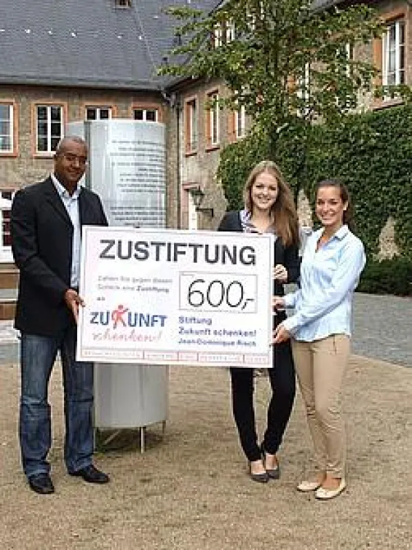 Luisa Wölbert (rechts) und Pia Schlote (links) überreichen die Zustiftung an Jean-Dominique Risch