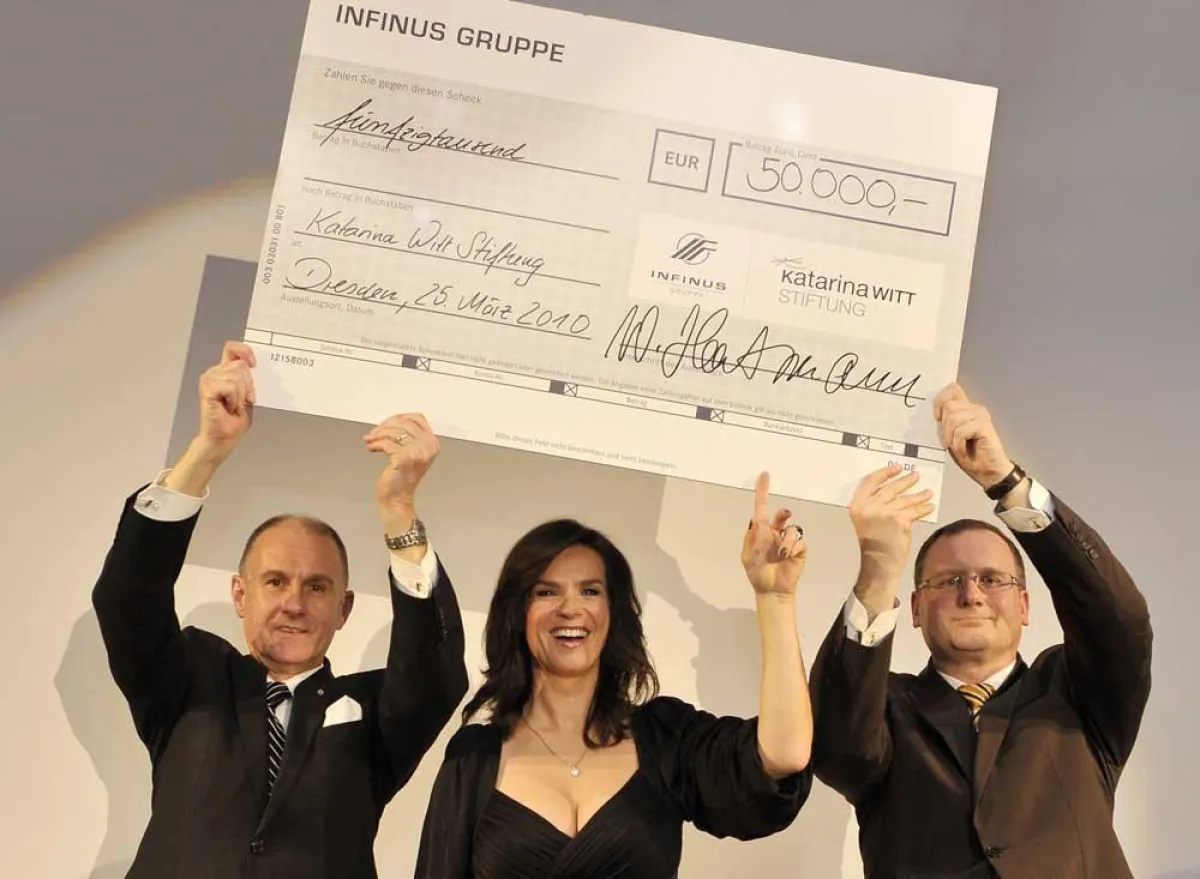 Wilhelm Hartmann (links) und Jens Pardeike (rechts), beide Vorstand der INFINUS AG Finanzdienstleistungsinstitut, zur Spendenübergabe mit Katarina Witt