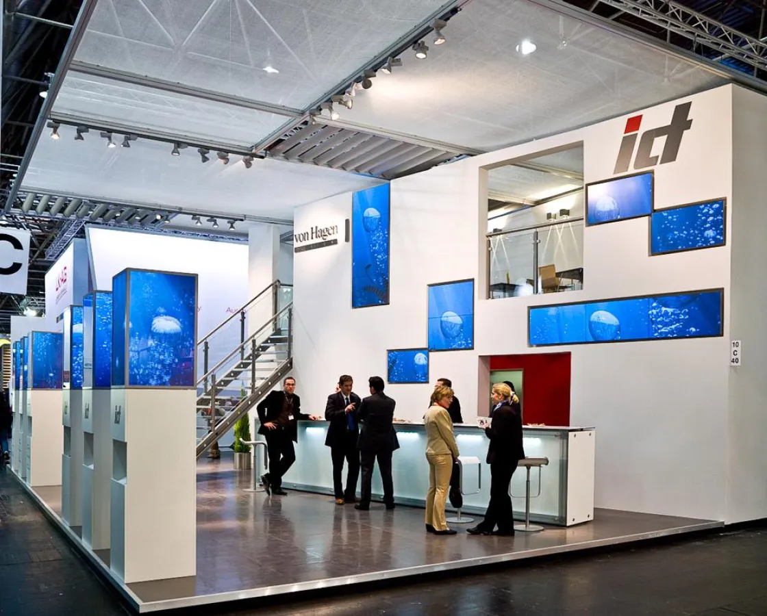 Ausgefallene Mediatektur auf dem ict-Messestand: Steglos FlatScreen Mosaik in der Standwand und sechs Steglos FlatScreen Tower