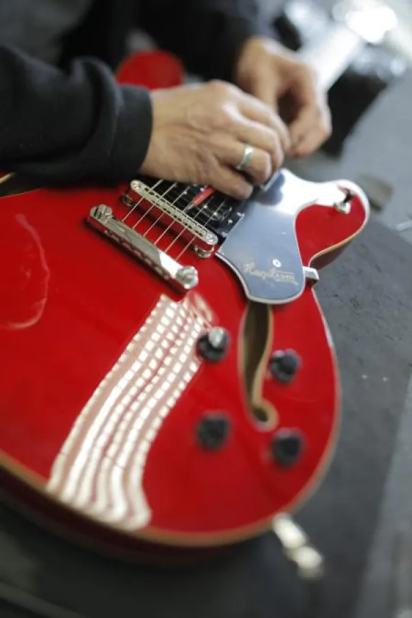 Qualitätskontrolle einer elektrischen Gitarre im Warenausgang der Musik Meyer Gruppe.