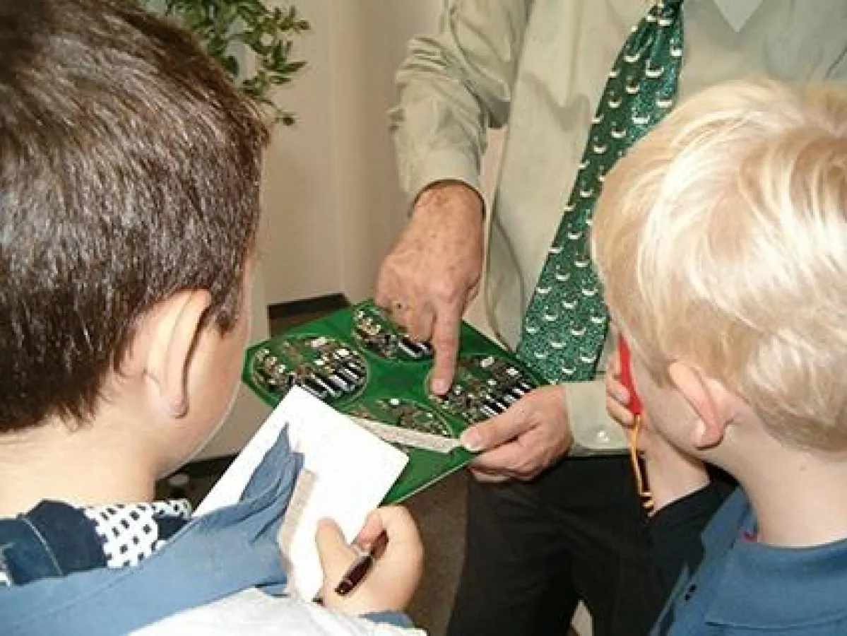Engagierter Unternehmer erklärt interessierten Kindern den Aufbau einer Leiterplatte