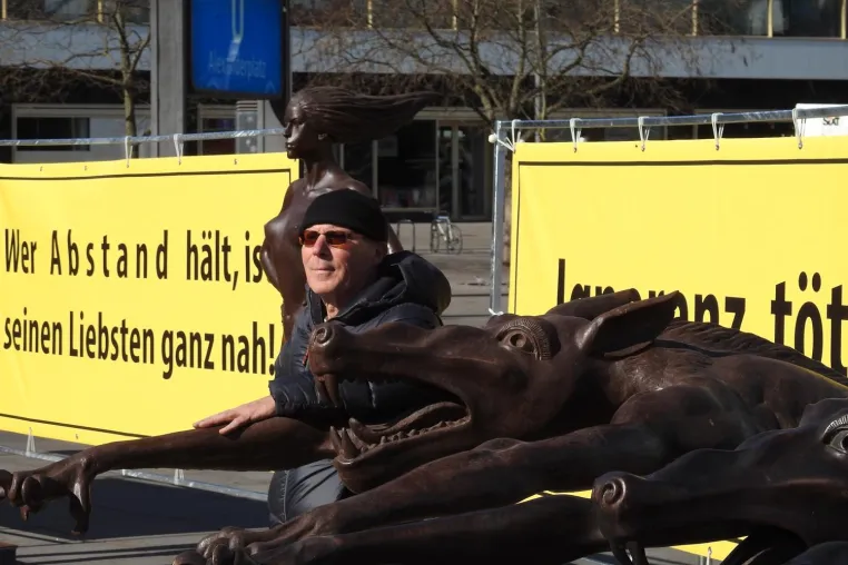Bild: Bronzefiguren in Berlin mahnen: „Ignoranz tötet“ und „Wer A b s t a n d hält, ist seinen Liebsten ganz nah.“