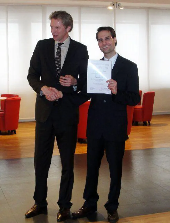 Sven Hardersen, Standortleiter der EUFH in Neuss, überreicht dem frisch berufenen Professor seine Er