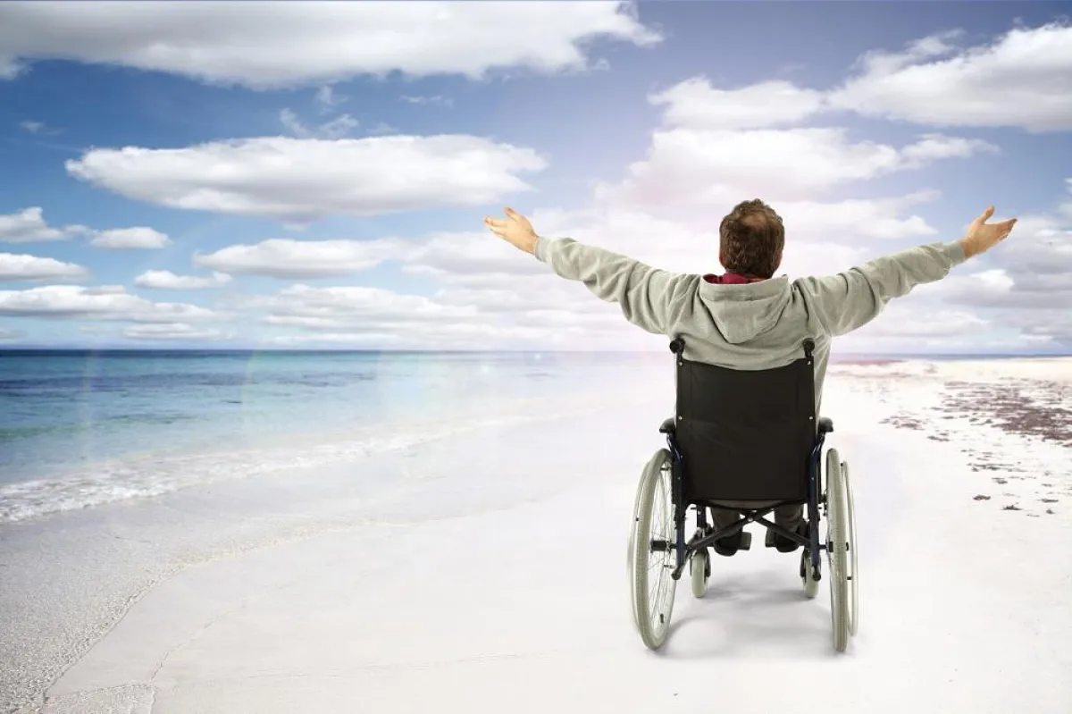 Glücklicher Urlauber mit Rollstuhl am Strand