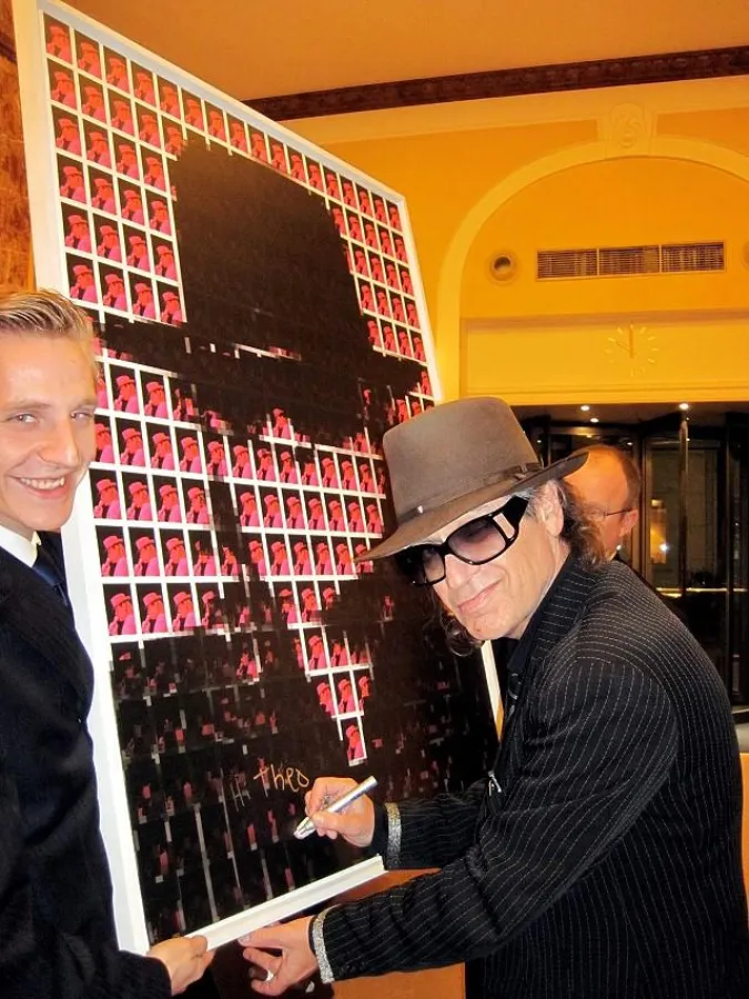 Udo Lindenberg signiert sein von Theo Hues geschaffenes Portrait