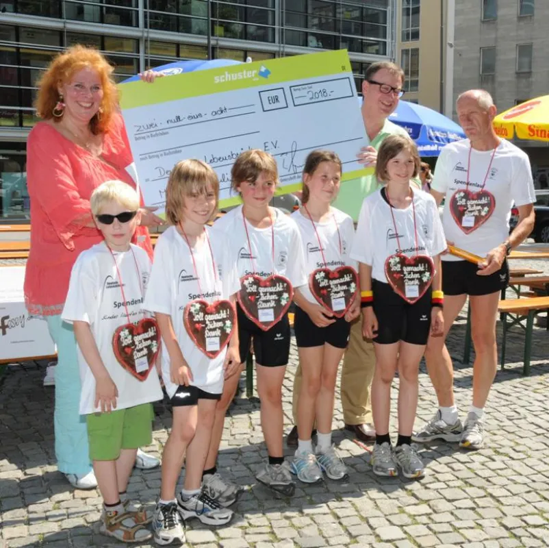 Scheckübergabe von Florian Schuster an Petra Windisch mit Läufern der Aktion