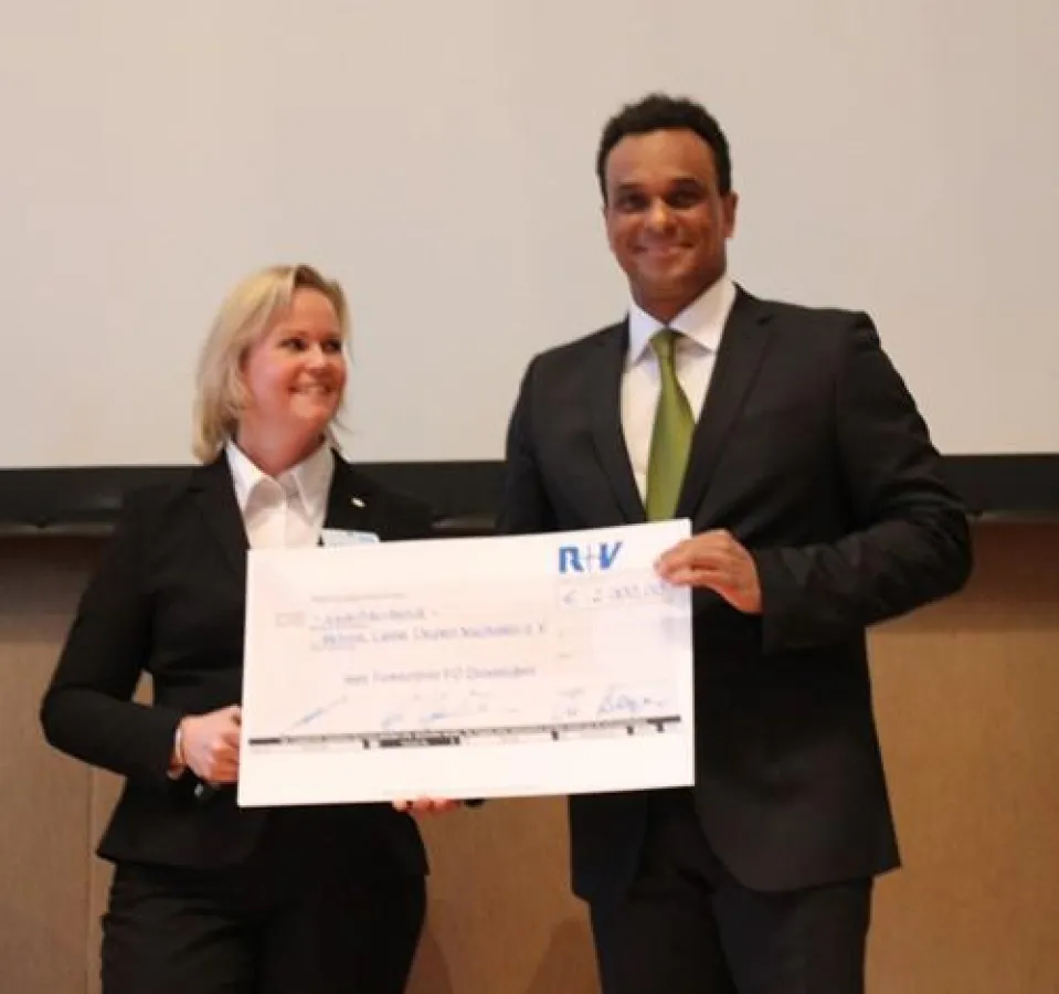 Der Vereinsvorsitzende Martin Rietsch freut sich über einen Scheck der R+V