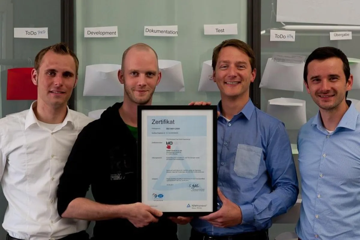 Gerahmte Qualität: HDNET-Mitarbeiter mit dem ISO-Zertifikat