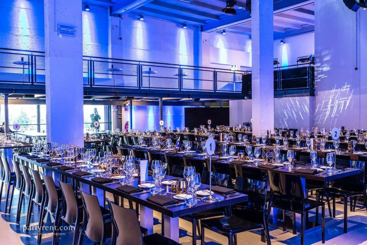 Unter der effektvollen Lichtinstallation strahlen die schwarzen Nancy Stühle im Umspannwerk