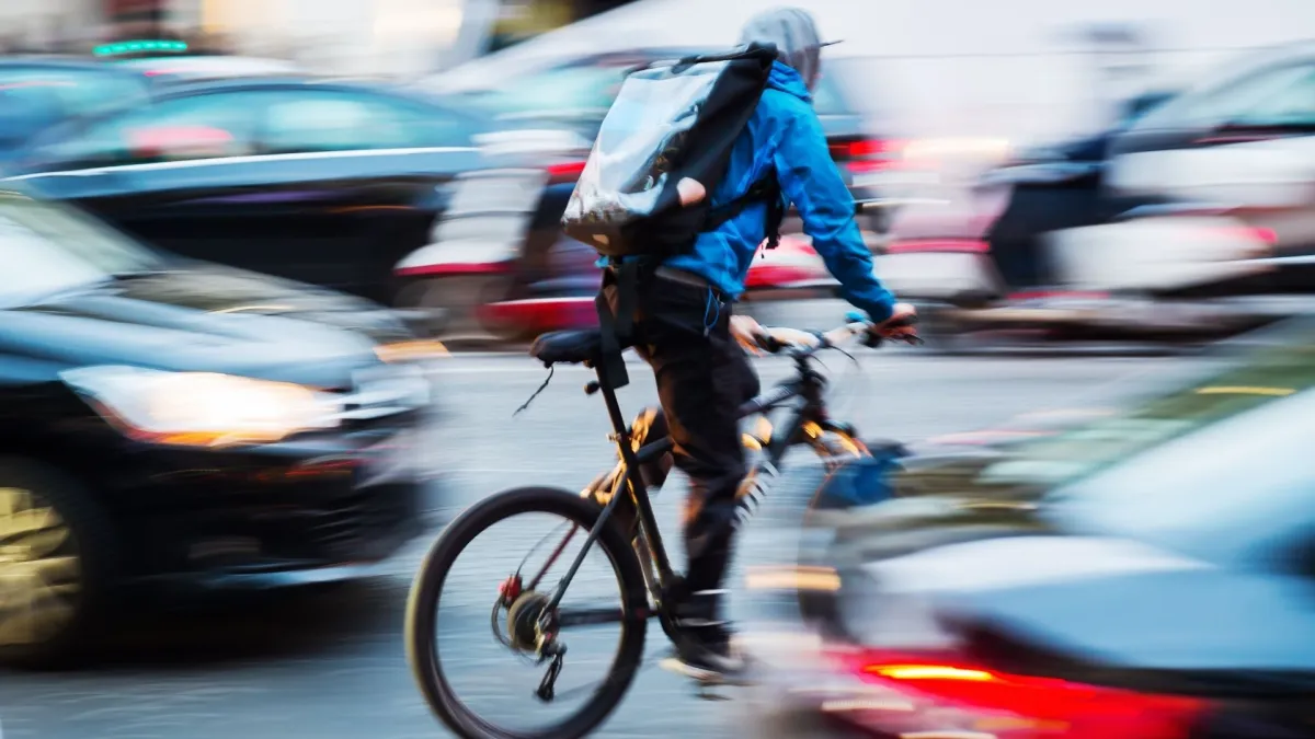 picture of a bicycle messenger in busy city traffic with camera made motion blur effect (© Christian Müller - stock.adobe.)