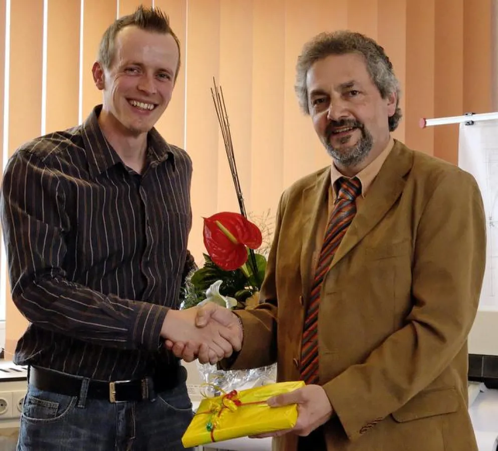 : Robert Kress (re.), Leiter der Expectra-Niederlassung in Kassel, begrüßte Sven Cherouni (li.) , den 200. Expectra-Projektmitarbeiter, mit einem Fachbuch und einem Blumenstrauß.