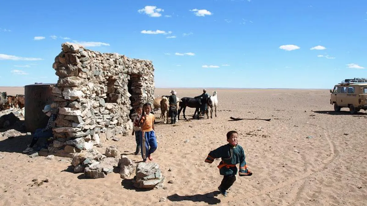 Neugierige Kinder an einer Wasserstelle in der Gobi wüste