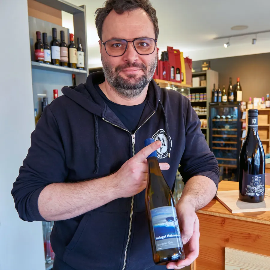 Frank Pietschmann mit einer Flasche original Rügener Weißweins aus dem Weingut Hohmann (© Ostseeappartements Rügen)