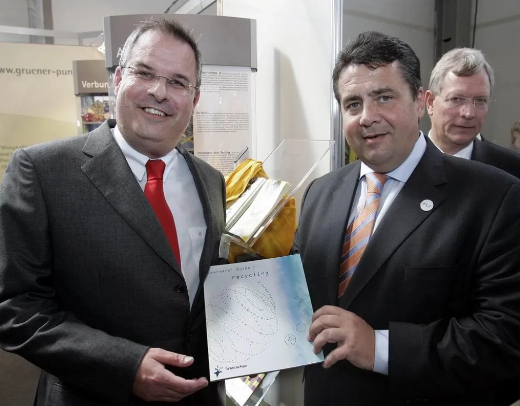 Stefan Schreiter, DSD GmbH (l.), überreicht Bundesumweltminister Sigmar Gabriel den Learners\' Guide Recycling. Rechts im Bild NRW-Umweltminister Eckhard Uhlenberg.